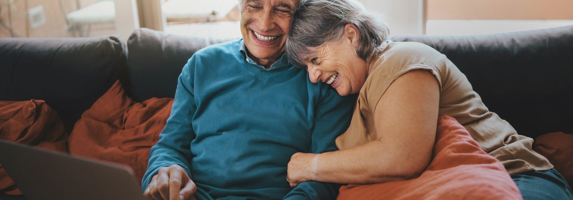 Retired couple watching funny video content on a laptop screen